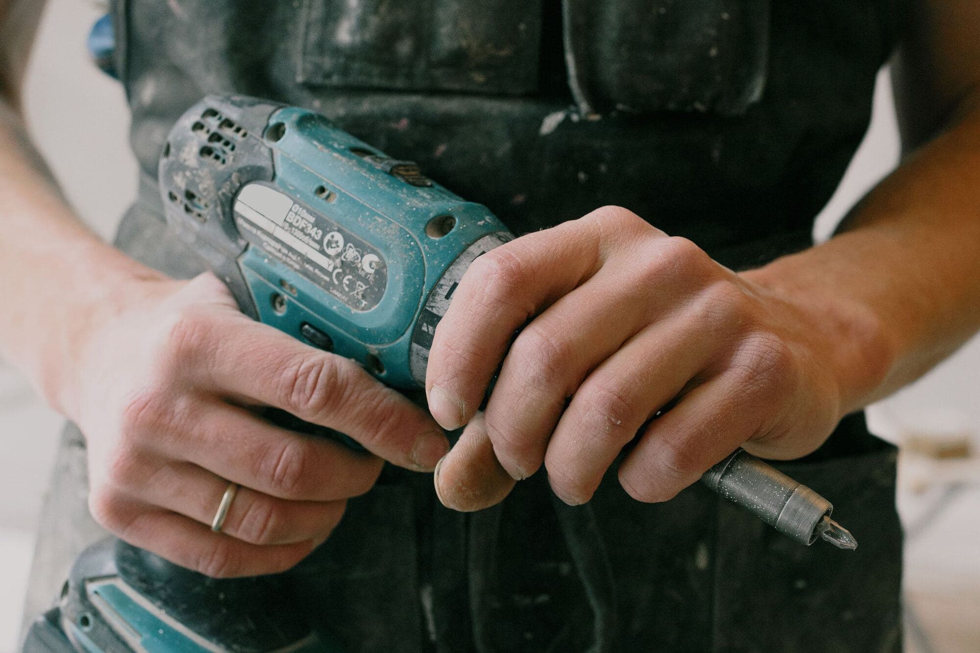 Close-up of hands driving a screw with a cordless drill
