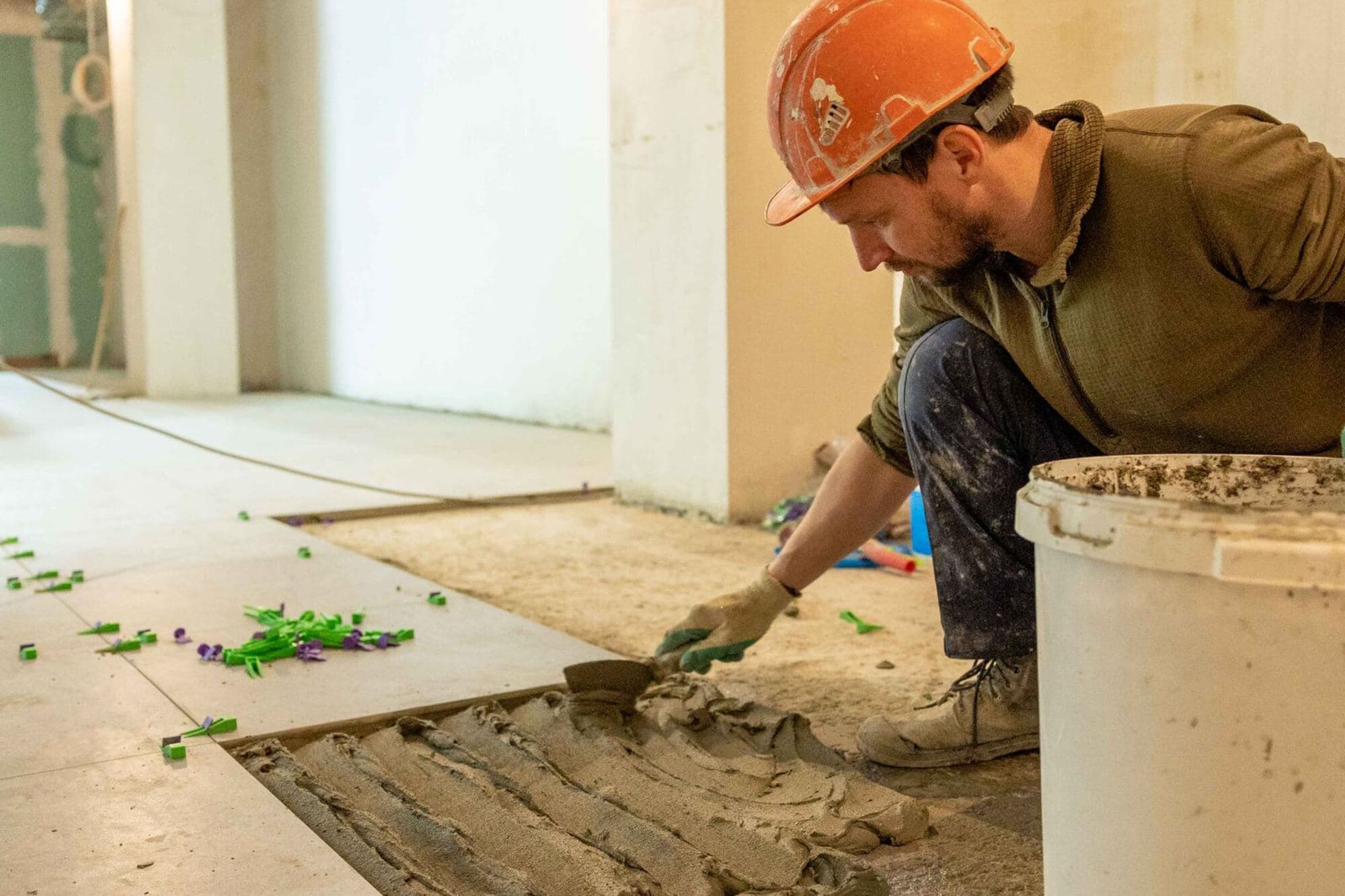 Worker spreading mortar over a bare subfloor during a remodel